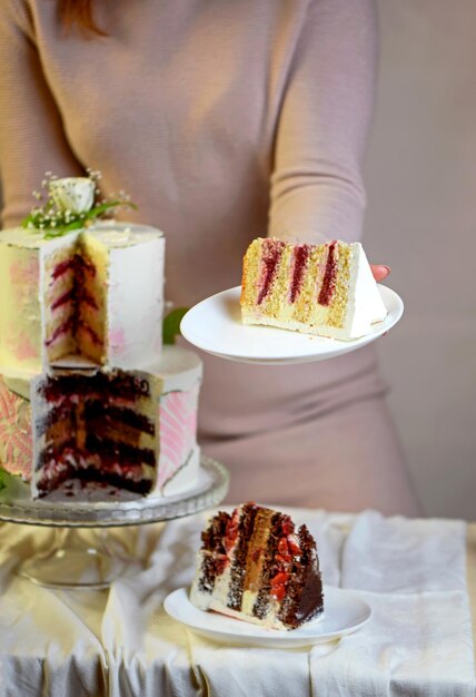 Confectioner prepares cuts and serves a festive wedding twotiered cake decorated with fresh flowers on a gray background