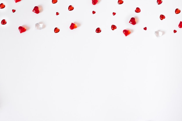 Confetti of red hearts. scatter of a cornered border on a white Valentine background