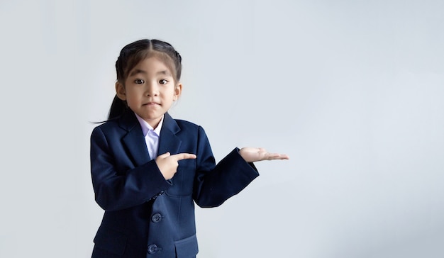 Confidence asian kid in uniform open hand and point to present in space