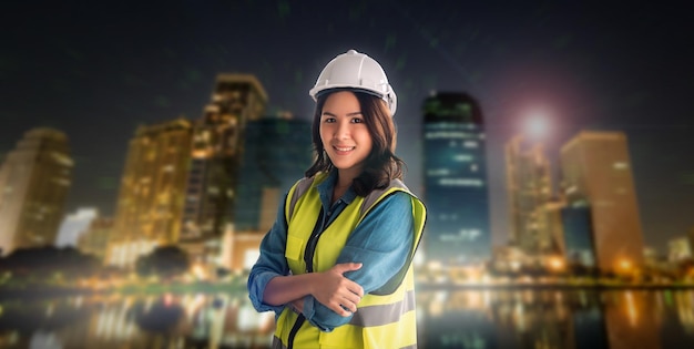 Confidence Female Civil Engineer with safety equipment with night modern city in the background for City Development cocept