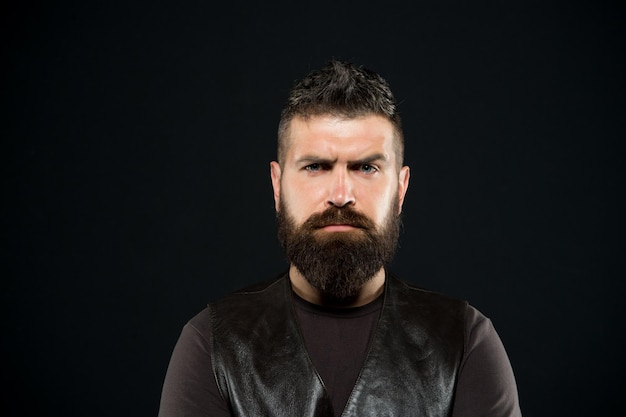 Confidence makes man look his best. Serious man dark background. Bearded man with hipster hair. Brutal man with mustache and beard. Barbershop. Hair salon. Fashion and style. Trendy hipster style.