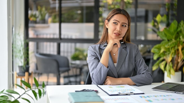 Confident Asian businesswoman pondering and thinking business strategy plan