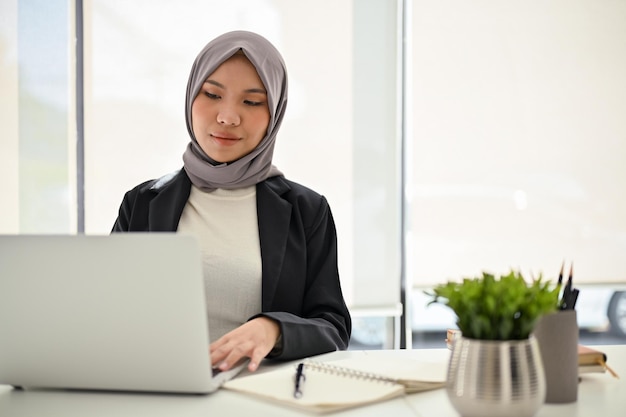 Confident Asian Muslim businesswoman using laptop working in the office