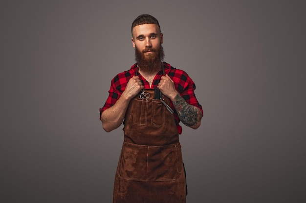 Confident bearded hairdresser adjusting apron