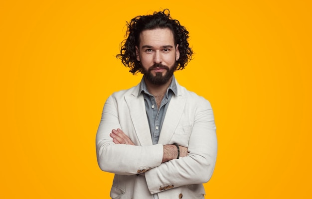 Confident bearded man in formal wear standing with crossed arms