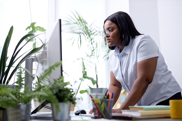 Confident black lady typing on keyboard on pc computer working alone in office beautiful american la...