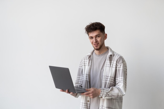 Confident business expert Confident young handsome man holding laptop and smiling while standing against white background