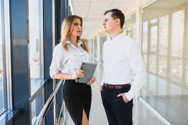 Confident business partners walking down in office building and discussing work