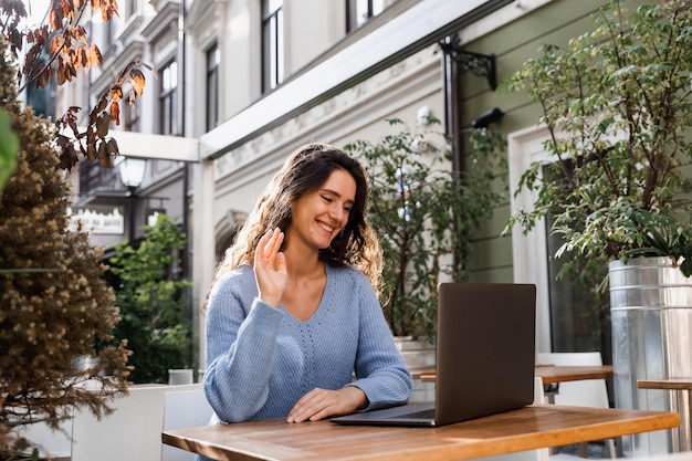 Confident business woman is chatting using laptop with colleagues via video connection and discussing new ideas Happy girl with laptop is chatting with her friends and family outdoor in cafe