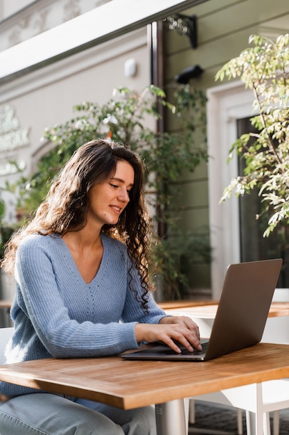 Confident business woman manager with laptop is working with colleagues online in cafe Attractive girl freelancer is working online on laptop in cafe outdoor