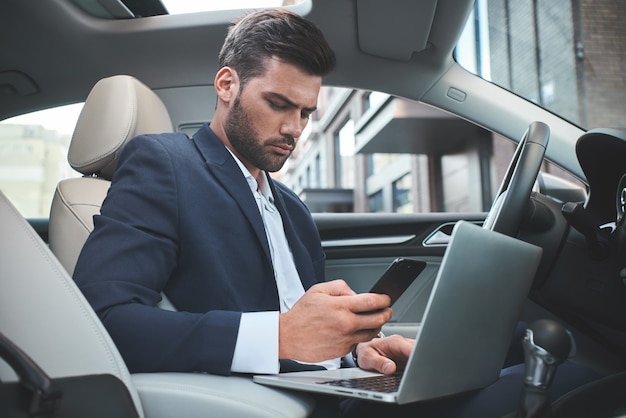 Confident businessman businessman with laptop in the car