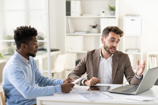 Confident businessman making presentation of online data to african colleague