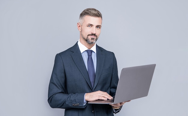 Confident businessman man in businesslike suit typing on laptop checking email