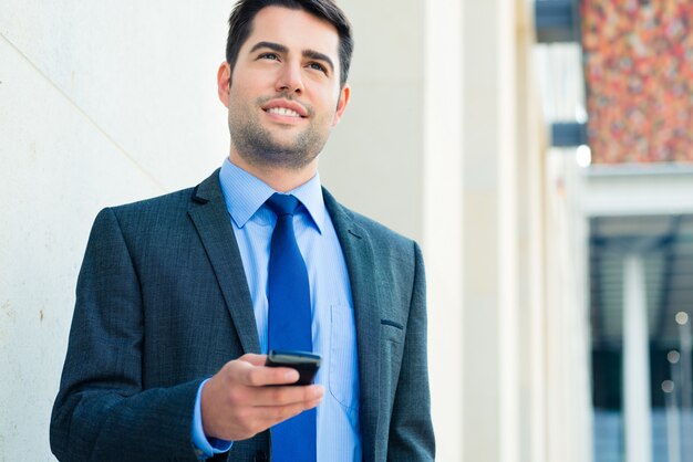 Confident businessman outdoor using phone