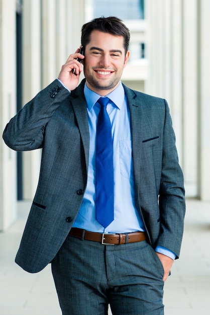 Confident businessman outdoor using phone