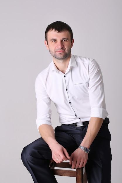 Confident businessman. Young handsome man in shirt standing on white wall.