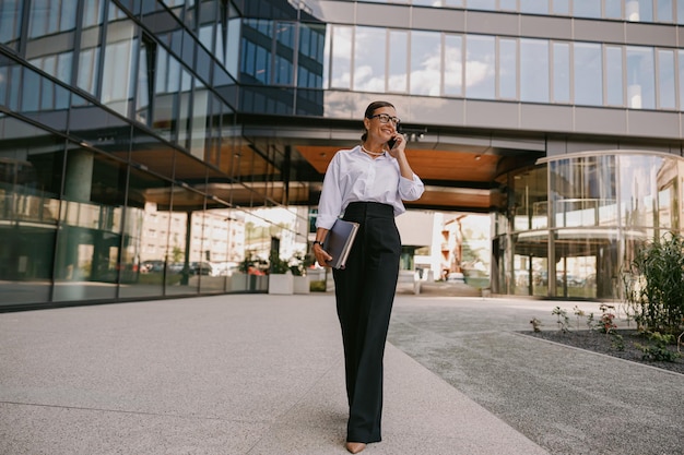 A confident businesswoman is walking gracefully in an urban environment with purpose and focus