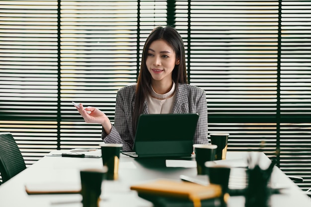 Confident businesswoman team leader sitting at boardroom and talking with staff at formal meeting briefing