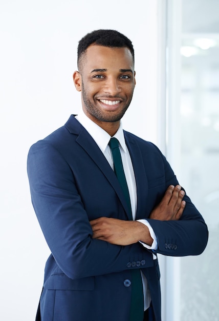 Confident corporate charm A handsome young african american businessman standing indoors with his arms folded