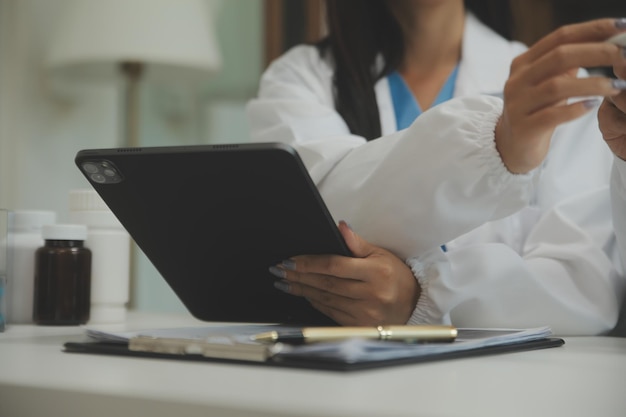 Confident doctor man holding a pill bottle and writing while talking with senior patient and reviewing his medication at office room