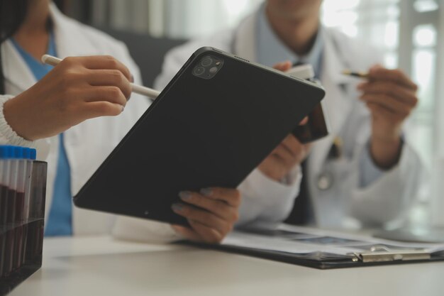 Confident doctor man holding a pill bottle and writing while talking with senior patient and reviewing his medication at office room