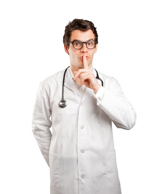 Confident doctor with silence gesture against white background