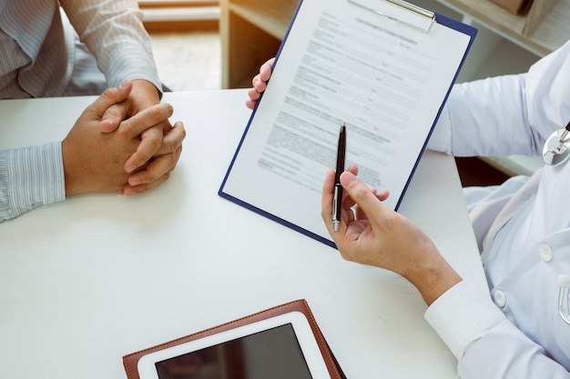 Confident female doctor reviews patient medical information and pointing to medical forms