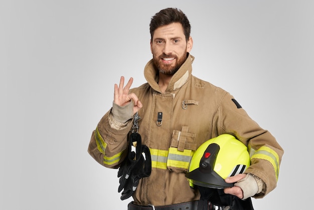 Confident firefighter showing ok sign while smiling at camera