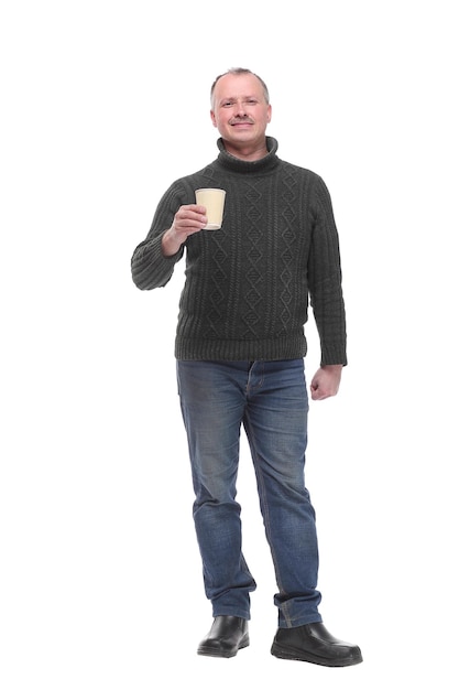 Confident handsome man in jeans holding cup with hot drink and smiling