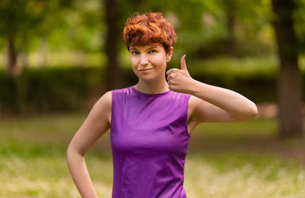 Confident lesbian woman gesturing thumb up in park