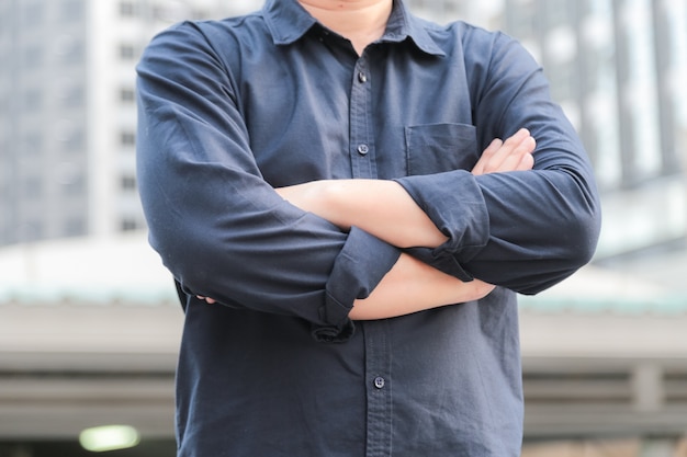 Confident male business executive  with arms crossed standing in front of office building