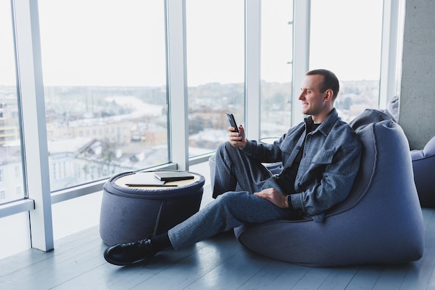 Confident male manager sitting in a modern workspace at a laptop and talking on the phone remote work