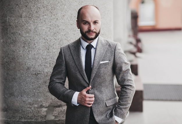 Confident man in formal suit poses against the background of city. Concept of a real estate manager or lawyer career