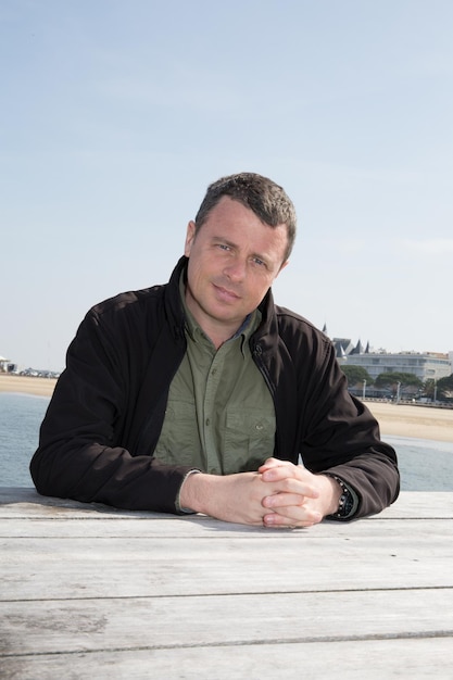 Confident  man standing close to ocean smiling at camera with the sea in the background