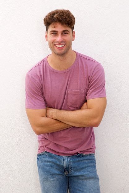 Confident man standing with arms crossed by white wall