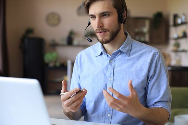 Confident man wearing headset speaking and watching business webinar training, listening to lecture.