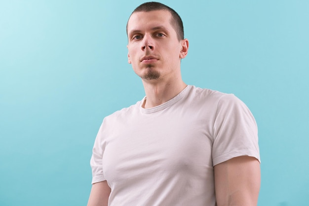 A confident man in a white tshirt looks on the sideway on a blue background Modern Studio White Young Casual Fashion Lifestyle Authority Concentration Hold