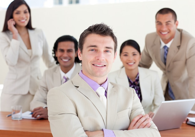 Confident manager with folded arms in front of his team