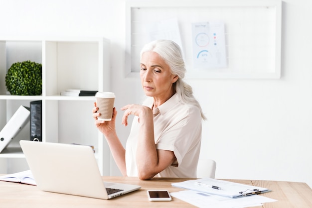 Confident mature business woman working on laptop