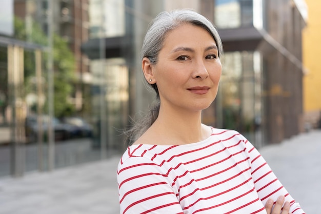 Confident mature businesswoman looking at camera standing on street Successful business