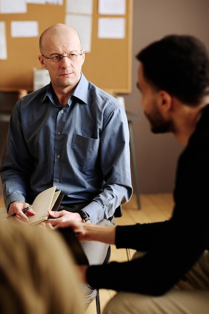 Confident mature counselor looking at patient with post traumatic disorder