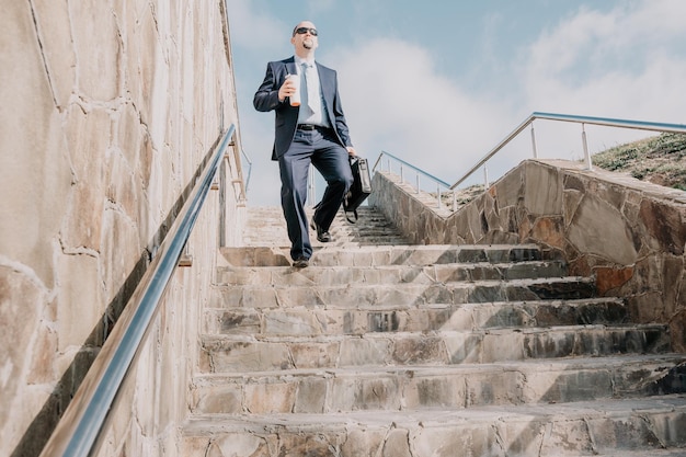 Confident middle age businessman with briefcase walking upstairs closeup of businessman wearing blue