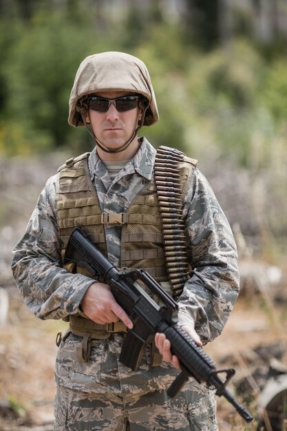 Confident military soldier standing with rifle in boot camp