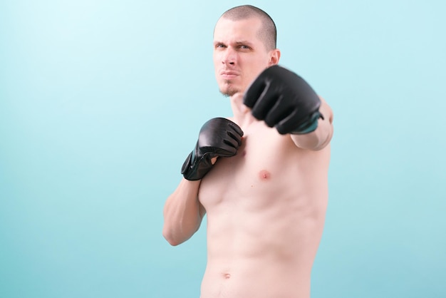 A confident MMA fighter in black gloves ready to fight on a blue background Fighting stance Pose Gloves Hero Powerful Endurance Fighting Combat Conflict Instruction Punching Box Knockout