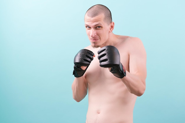 A confident MMA fighter in black gloves ready to fight on a blue background Fighting stance Pose Knockout Artist Bald Mixed Martial Arts Hit Heavy Tough Good Satisfied Hitting Win Goal