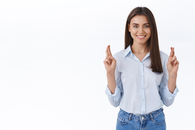 Confident and optimistic hopeful young woman cross fingers for good luck, believe everything be fine, praying for goodwill dream come true, looking camera and smiling as sure wish fulfill