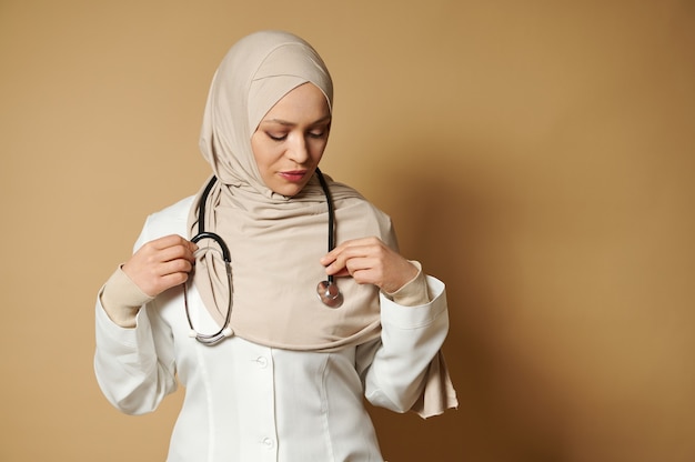 Confident portrait of a muslim woman doctor wearing hijab and putting a phonendoscope around her neck