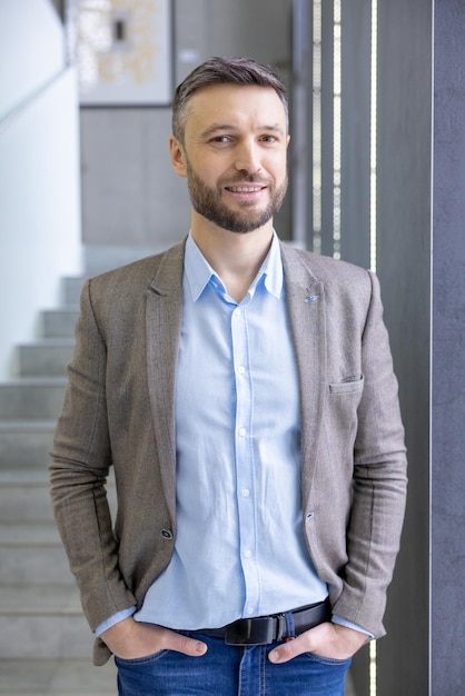 Confident professional man in smart casual attire smiling in modern office setting portraying