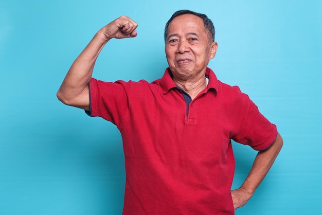 Confident satisfied senior Asian man raises arm and show biceps hand muscle demonstrate strong power