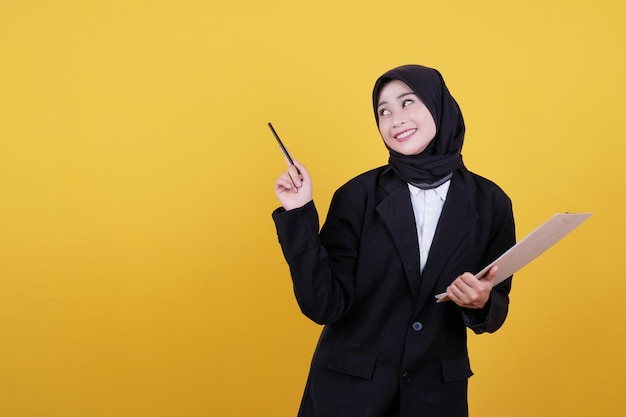 Confident smiling businesswoman pointing to left on yellow